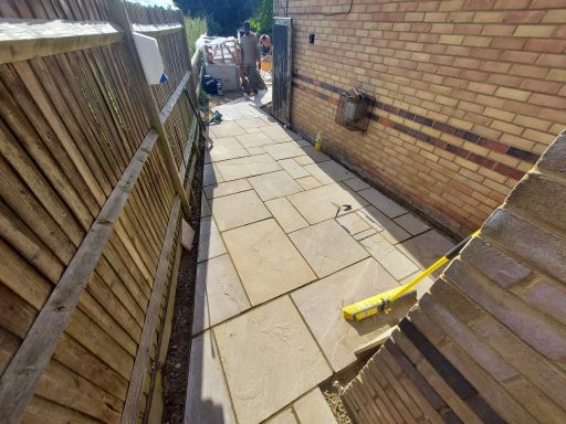 Paved walkway between two buildings, with tools and equipment visible in the background.