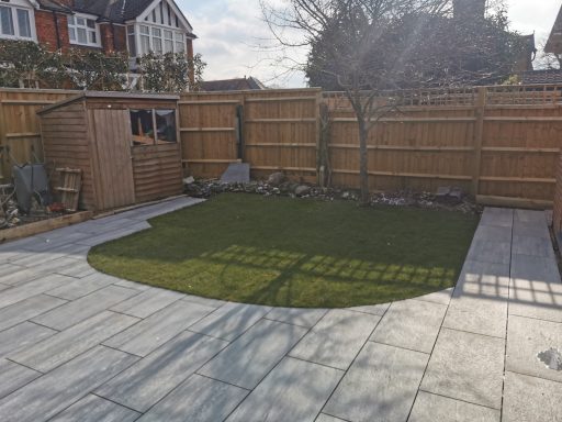 Neatly landscaped garden with artificial grass, paving, and wooden fencing.