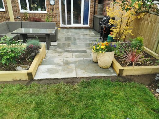 Patio with seating area, flower pots, and landscaped garden.