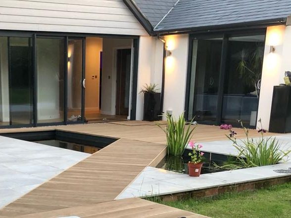 Landscaping project in Gerrards Cross featuring porcelain patio and bridge over fish pond by ESI Building