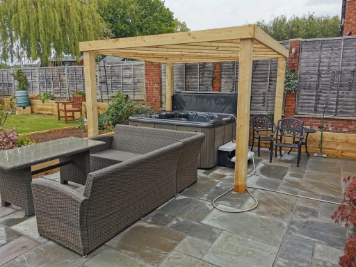 Garden seating area with a wooden gazebo, outdoor furniture, and stone patio.