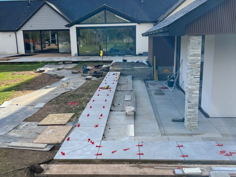 Newly constructed patio with paving stones and surrounding landscaping work in progress.