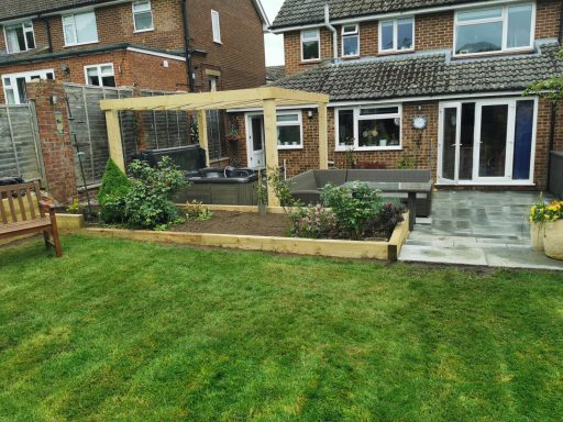 Landscaping project in Gerrards cross with wooden pergola, seating area, and flower beds.